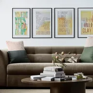 A well-decorated living room featuring a plush couch, a coffee table with magazines, a fireplace, and walls adorned with stunning wall art.