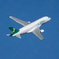 A Pakistan International Airlines (PIA) Airbus A380, in mid-flight against a clear blue sky, sunlight gleaming off its green and white livery.