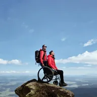 Man on a wheelchair seeated on top of a mountain
